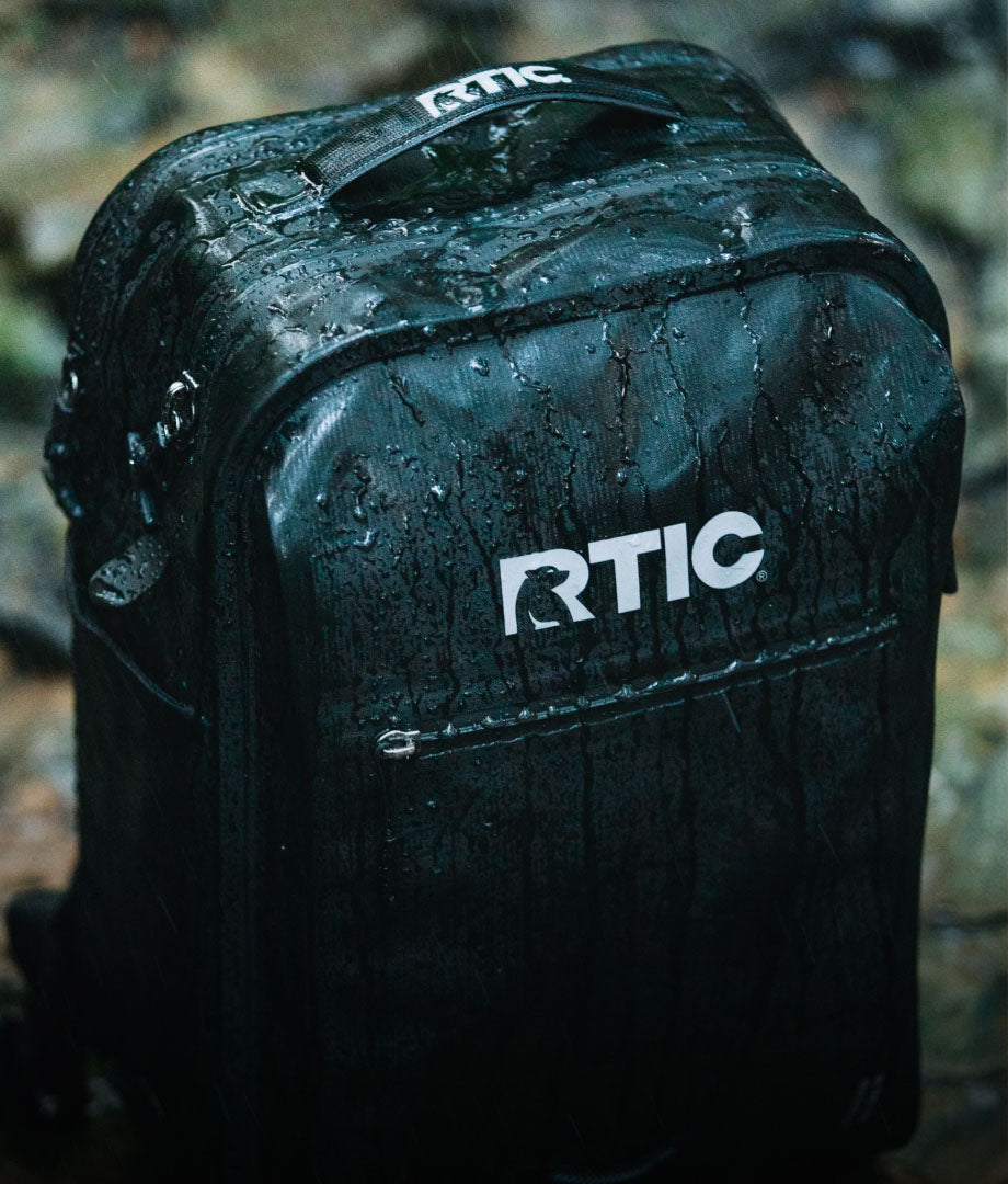 A close-up on a black RTIC Ultra-Dry Backpack in the rain.